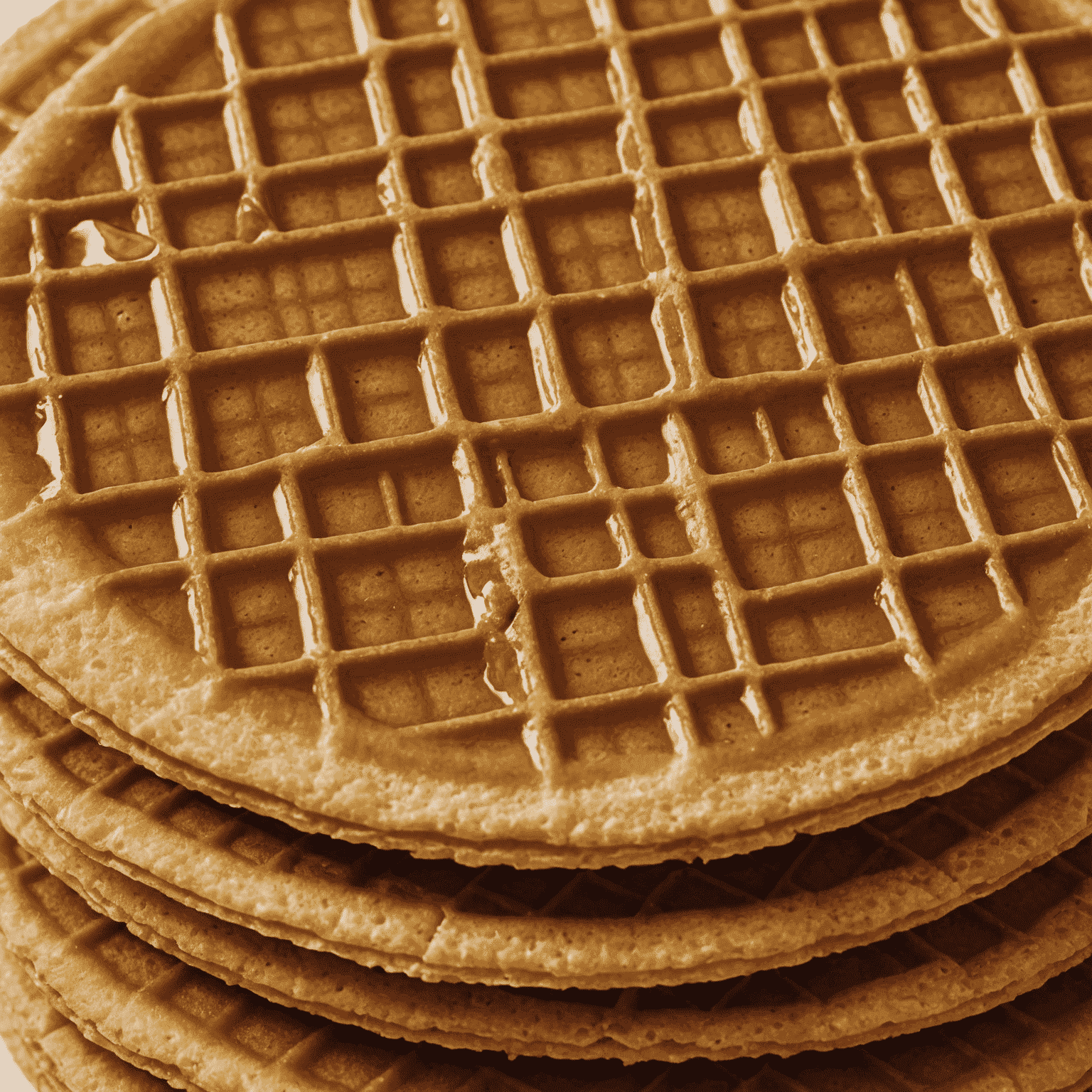 Close-up foto van een traditionele Nederlandse stroopwafel met een gouden, knapperige buitenkant en een zachte, karamelachtige vulling binnenin.